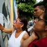 People check their voting machine at a list of voters provided by Venezuelan National Electoral Council, CNE, outside of a poll station 