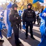 New York Police Department officers hold their position as parade participants walk around