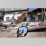 Women are reflected in a motorbike's mirror as they access the damaged building after an earthquake in Pidie Jaya, Aceh province, Indonesia.
