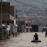 A man plays in a flooded street using an inner tube in Lima, Peru.