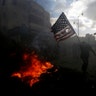 A Palestinian protester prepares to burn a U.S. flag near the Jewish settlement of Beit El, in the West Bank city of Ramallah, December 7