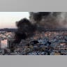 A_column_of_smoke_rises_from_buildings_during_clashes
