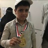 A young student shows off his medal among counselors and staff at the KS Relief Center in Yemen.