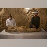 Egyptian excavation workers restore a mummy in a newly discovered tomb on Luxor's West Ban