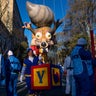 Participants stand below a parade balloon before the Macy's Thanksgiving Day Parade begins