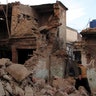 A resident walks past the rubble of a house