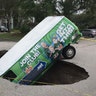 A boy photographs a van in a sinkhole in Winter Springs, Fla., Monday