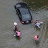 Residents wade through floodwaters as they evacuate their homes as floodwaters from Tropical Storm Harvey rise Tuesday, in Houston