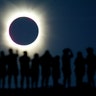 Tourists watch the sun being blocked by the moon during a solar eclipse in the Australian outback town of Lyndhurst, December 4, 2002