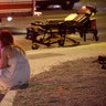 A woman sits on a curb at the scene of a shooting outside of a music festival along the Las Vegas Strip, Sunday