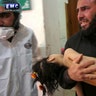 Man carrying a child following a suspected chemical attack at a makeshift hospital in the town of Khan Sheikhoun