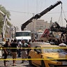 Iraqi security forces remove destroyed vehicles at the site of a deadly bomb attack, in Baghdad, Iraq