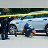 An FBI crime scene investigator searches under a car for evidence at the scene of a multiple shooting in Alexandria, Va., Wednesday
