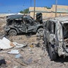 A Somali soldier walks past destroyed vehicles at the scene of a car bomb attack in Mogadishu, Somalia