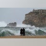 A couple watch the waves breaking in Nazare, Portugal, strong winds and waves up to 14 meters (47 feet) high were expected along the Portuguese coast .