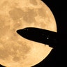 An aircraft taking off from Ronald Reagan National Airport is seen passing in front of the moon as it rises in Washington, December 3