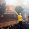Los Angeles firefighters battle to contain flames on a burning home in the Bel Air district of Los Angeles, Wednesday