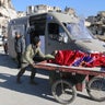 A man pushes a cart with a woman lying on it as vehicles wait to evacuate people from a rebel-held sector of eastern Aleppo, Syria December 15, 2016. 