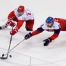 Russian Sergei Andronov and Jan Kolar of the Czech Republic, battle for the puck in their semi-final ice hockey match at the Winter Olympics