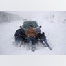 A group of men help a motorist after his vehicle was stuck in the snow near the Asbury Park, N.J. boardwalk, Thursday