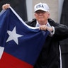 President Donald Trump holds up a Texas flag after speaking with supporters outside Firehouse 5, Tuesday, in Corpus Christi