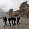 Armed police officers patrol in the courtyard of the Louvre museum near where a soldier opened fire after he was attacked in Paris, Friday, Feb. 3, 2017.