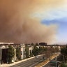 A large plume of smoke from a brush fire rises over the city of Orange