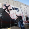 A Palestinian man crosses out a mural depicting U.S. President Donald Trump on the Israeli barrier, in Bethlehem, December 7