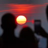 People watch the setting sun from the top of One World Trade Center in New York City, August 20