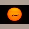 A plane taking off from Newark Airport passes through the setting sun seen from One World Observatory in New York City, August 20