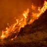 Flames from the Thomas fire burn above traffic on Highway 101 north of Ventura, California, Wednesday