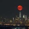 The moon rises over One World Trade Center in lower Manhattan as seen from West Orange, NJ on Saturday