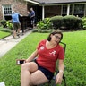 Natalie Hausman-Weiss sits on her front lawn as friends help remove furniture damaged by floodwaters in Houston, Wednesday