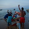 Fishermen from the Marval family give instructions to a skiff towing their boat to sea as they head out for a night of fishing in Punta de Araya, Sucre state, Venezuela.