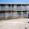 Prisoner hauling food that brought him, walks past a prison building at the National Penitentiary in downtown Port-au-Prince, Haiti.