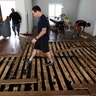 Michael Saghian walks across the living room of his home damaged by floodwaters 