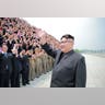 North Korean leader Kim Jong-Un waves as he participates in a photo session with officials 