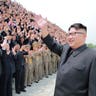 North Korean leader Kim Jong-Un waves as he participates in a photo session with officials 