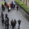 Armed police walk past emergency services attending to injured people on the floor outside the Parliament.