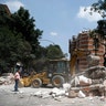 A bulldozer removes debris from a partially collapsed building