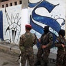 Soldiers stand guard close to a Mara Salvatrucha gang related graffiti in Soyapango, El Salvador