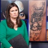 White House press secretary Sarah Huckabee Sanders stands in front of pictures of MS-13 gang tattoos