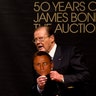 Moore holds a mask of Bond actor Daniel Craig during the 50 Years of James Bond Auction at Christies in London, October 5, 2012