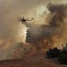 A firefighting helicopter drops water to help save a home during a wind-driven wildfire in Orange, California October 9, 2017