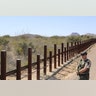 A Cochise County Sheriff officer stands along the border fence between the United States and Mexico.