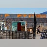 A woman is pictured at the patio of her house by a newly built section of the U.S.-Mexico border fence.