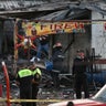 Firefighters and rescue personnel stand near a destroyed stand and gutted building after an explosion at the San Pablito fireworks market in Tultepec, Mexico.