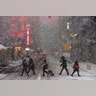 Pedestrians walk in Times Square as snow falls in New York.