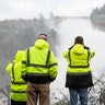 California Department of Water Resources personnel monitor water flowing through a damaged spillway.