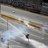 An opposition supporter is hit by a water cannon while clashing with riot security forces during a rally against President Maduro